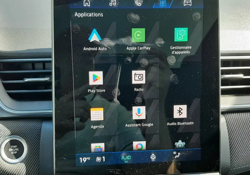 Écran tactile central du Renault Symbioz E-Tech gris rafale, affichant les applications connectées avec traces de doigts visibles.