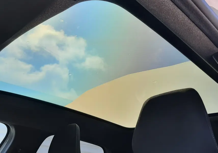 Vue intérieure du toit panoramique du Renault Symbioz gris Rafale, mettant en valeur le ciel visible à travers la large surface vitrée.