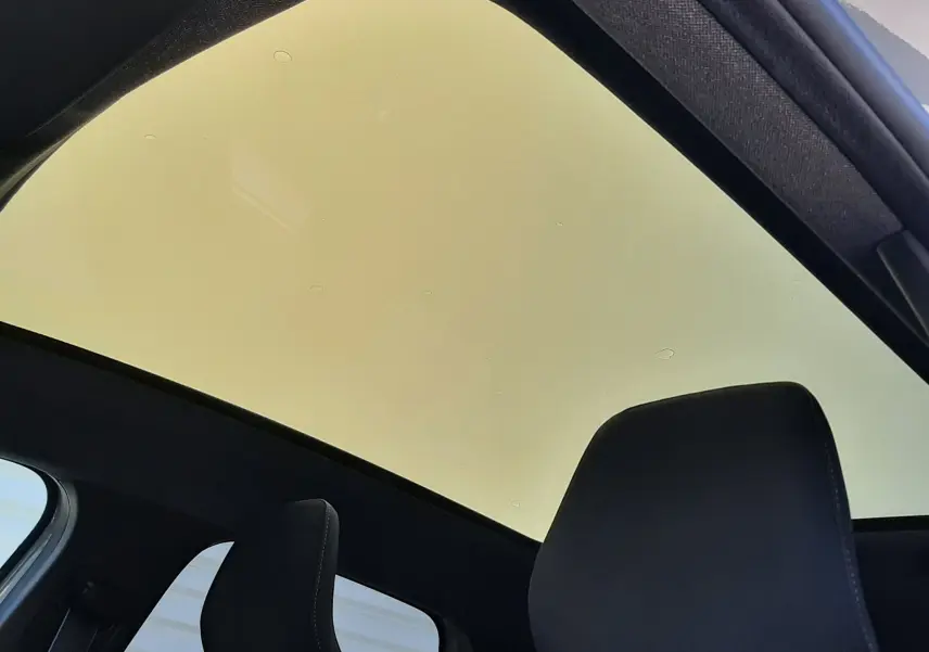 Vue intérieure du toit panoramique teinté et des appuie-têtes noirs du Renault Symbioz gris Rafale, version hybride 2025.