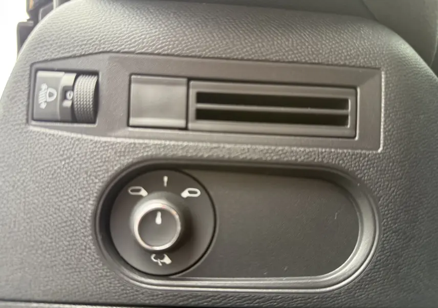 Gros plan sur la commande de réglage des rétroviseurs et la sortie d’air noire à l’intérieur d’une DS3 hybride 2025.