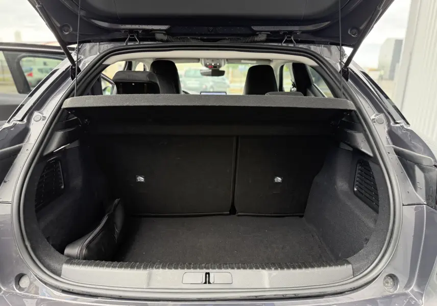 Vue arrière du coffre ouvert d'une DS3 hybride 2025 gris Vol de Nuit avec toit noir, montrant l'espace de chargement vide.