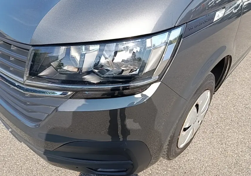Gros plan sur l'avant droit gris foncé du Volkswagen Transporter 2.0 TDi avec phares et calandre visibles.