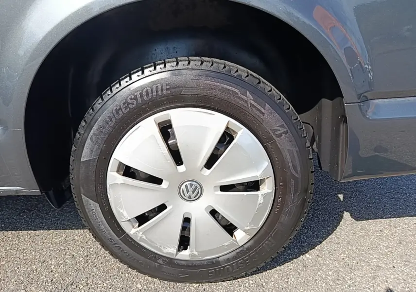 Gros plan sur la roue avant droite d’un Volkswagen Transporter gris foncé avec enjoliveur VW et pneu Bridgestone.