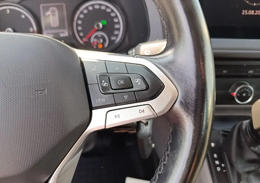 Gros plan sur le volant cuir multifonctions du Volkswagen Transporter 2.0 TDi 150 DSG7, tableau de bord en arrière-plan.