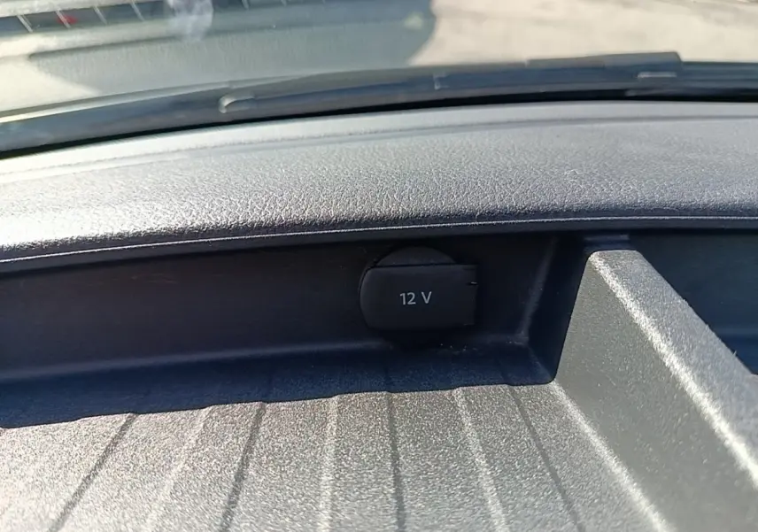 Prise 12V noire en gros plan sur le tableau de bord d’un Volkswagen Transporter gris foncé, vue intérieure frontale.