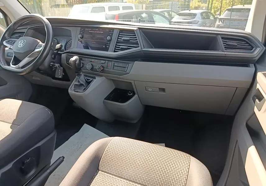 Vue intérieure côté conducteur du tableau de bord gris clair et volant cuir multifonctions du Volkswagen Transporter 2022.