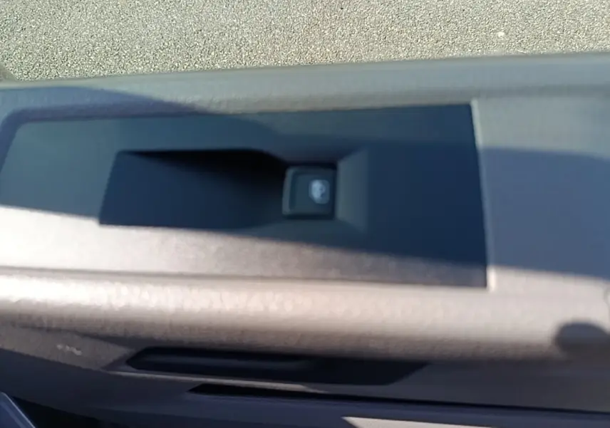 Gros plan sur le bouton de verrouillage centralisé sur la porte intérieure du Volkswagen Transporter gris foncé.