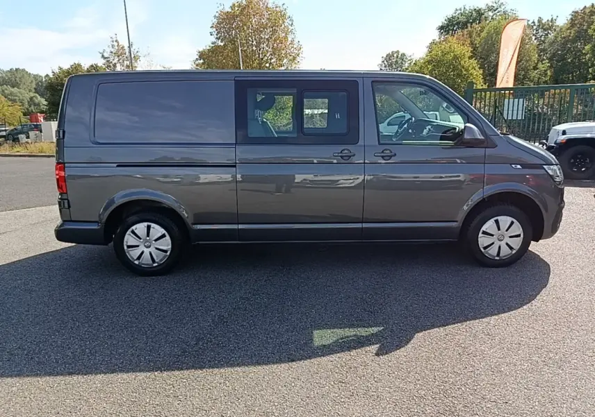 Vue de profil côté droit d’un Volkswagen Transporter gris foncé avec vitres avant et portières coulissantes arrière.