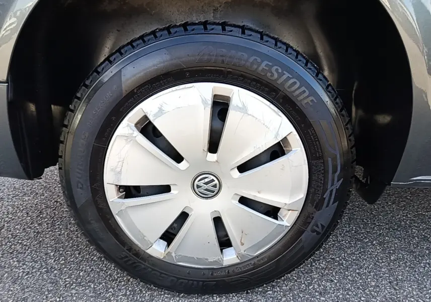 Gros plan sur la roue avant droite gris foncé du Volkswagen Transporter 2.0 TDi 150 DSG7 avec enjoliveur blanc marqué VW.