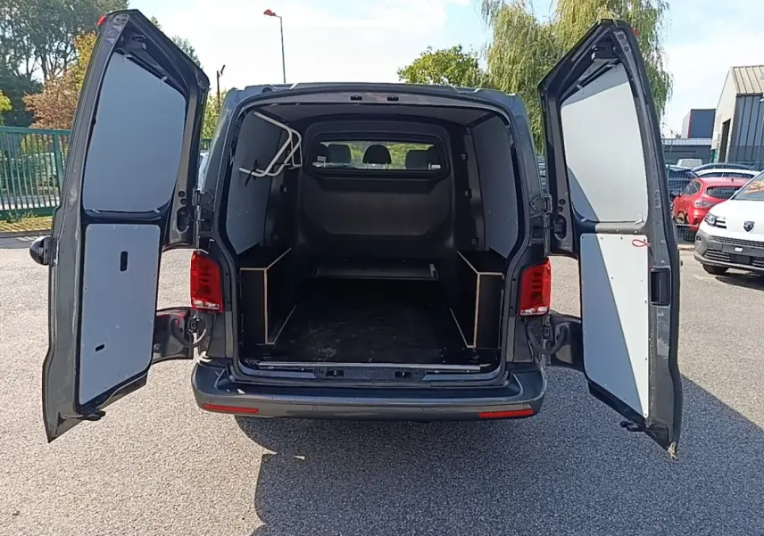 Vue arrière du Volkswagen Transporter gris foncé 2022 avec portes battantes ouvertes montrant l'espace de chargement vide.