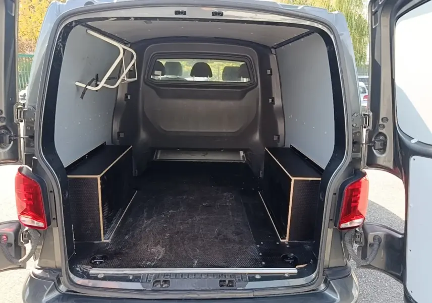 Vue arrière du Volkswagen Transporter gris foncé 2022 avec portes ouvertes et espace de chargement vide.