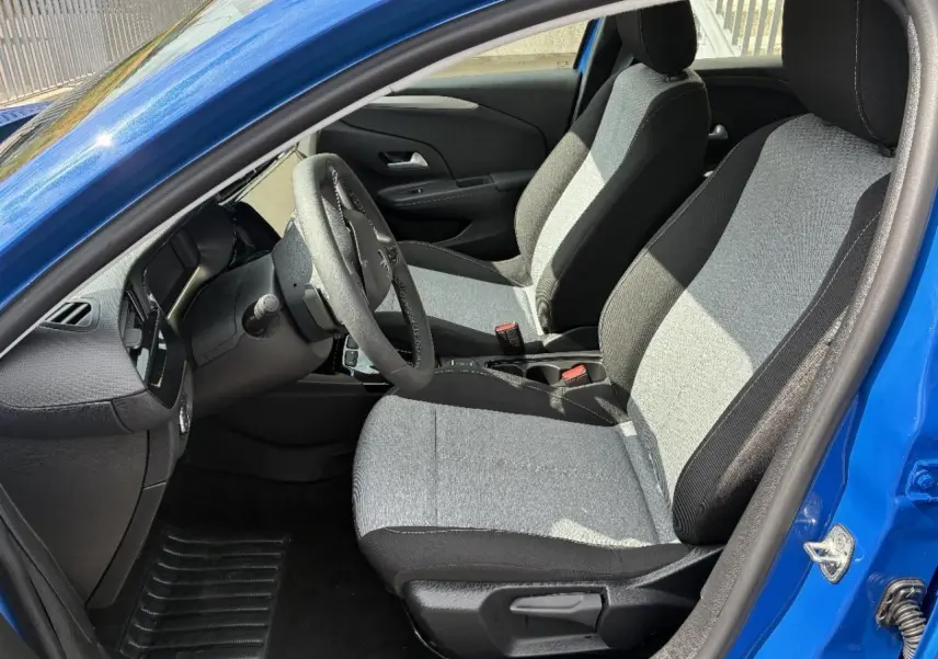Vue intérieure côté conducteur de l’Opel Corsa 2025 bleu voltaik, sièges tissu bicolore et tableau de bord moderne.