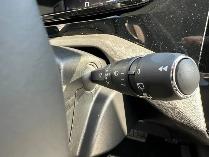 Gros plan sur la commande des essuie-glaces dans l'habitacle noir de la Peugeot 308 bleu 2025, côté gauche du volant.