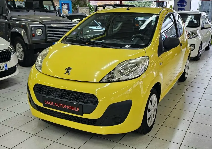 PEUGEOT 107 jaune vue 3/4 avant droit, compacte avec calandre noire et phares arrondis en showroom.