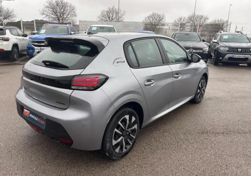 Vue 3/4 arrière droite d’une Peugeot 208 Hybrid gris 2025 avec jantes 16 pouces et logo Style sur aile arrière.