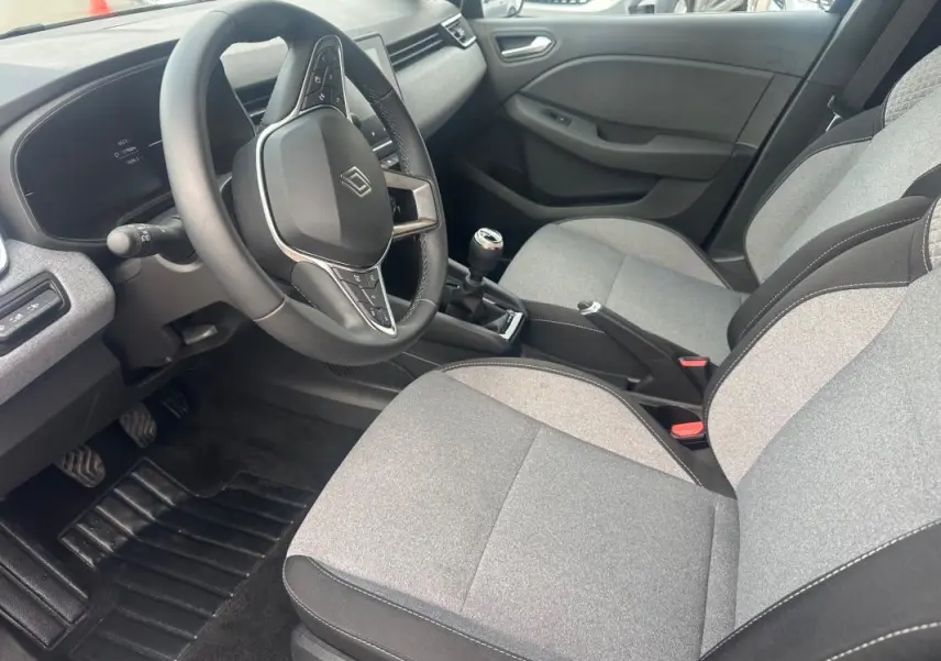 Vue intérieure côté conducteur de la Renault Clio V dCi 100 Evolution 2025, sièges gris, volant multifonction et boîte manuelle.