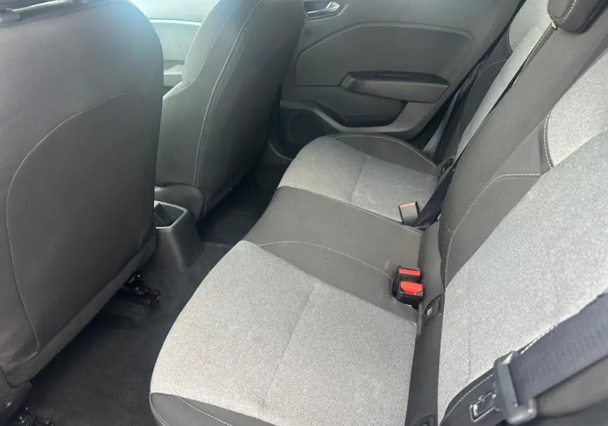 Vue intérieure arrière côté droit montrant les sièges bicolores gris et noir de la Renault Clio V dCi 100 Evolution 2025.