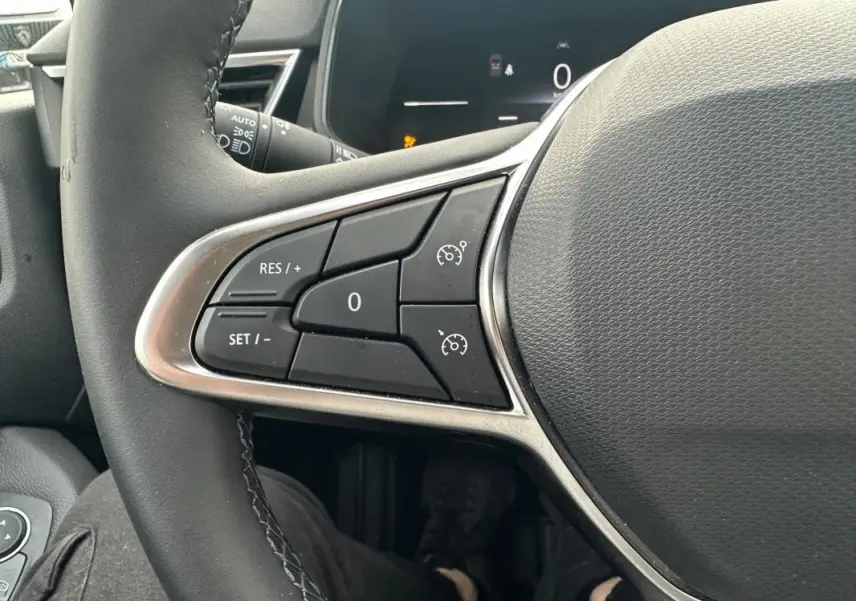 Gros plan sur les commandes de régulateur de vitesse au volant noir de la Renault Clio V dCi 100 Evolution 2025.