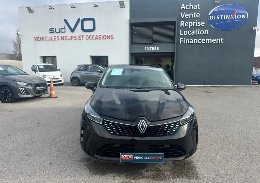 Vue avant d'une Renault Clio V dCi 100 Evolution noire stationnée devant un concessionnaire avec logo Renault visible.