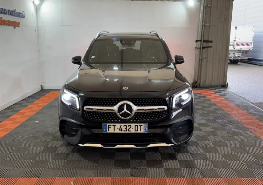 Vue avant d’un Mercedes GLB 200 d AMG Line noir avec phares LED allumés dans un garage.