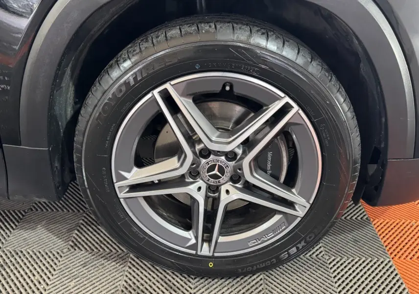 Gros plan sur la roue avant droite noire d’un Mercedes GLB 200 d AMG Line, jante alliage à cinq branches.