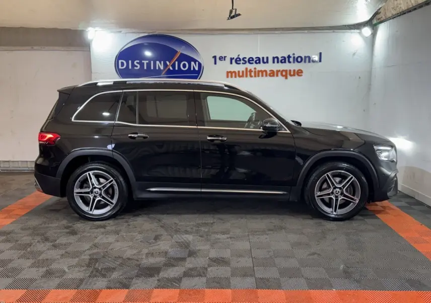Vue latérale droite d’un Mercedes GLB 200 d AMG Line noir, avec jantes alliage et rails de toit chromés.