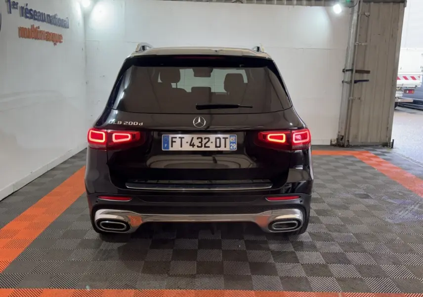 Vue arrière du Mercedes GLB 200 d AMG Line noir avec feux LED allumés dans un garage intérieur.