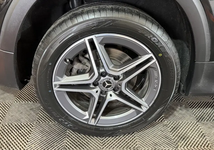 Gros plan sur la roue avant droite du Mercedes GLB 200 d AMG Line noir, avec jante AMG à cinq branches.