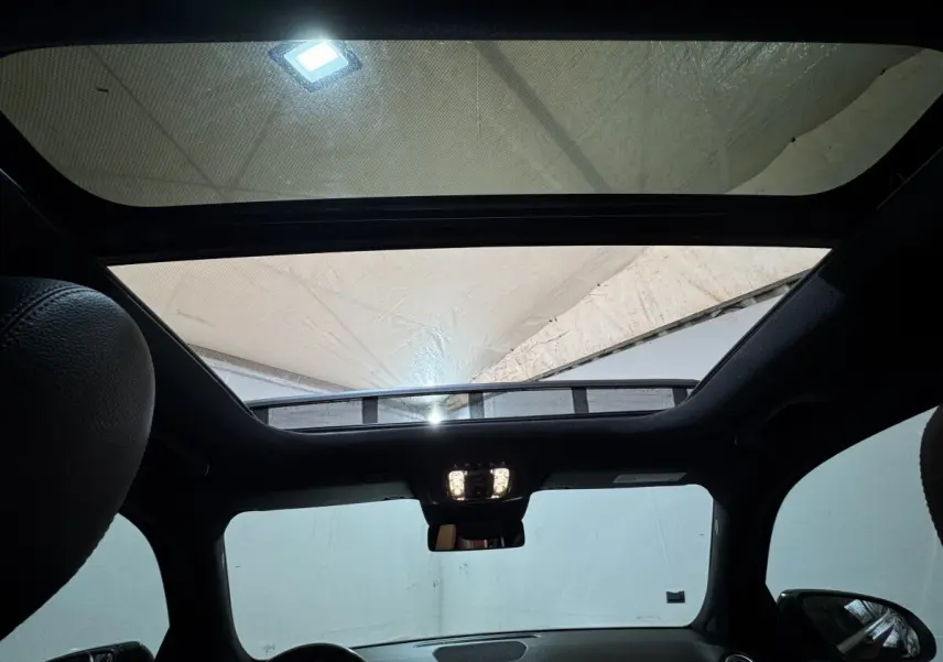 Vue intérieure du toit ouvrant panoramique du Mercedes GLB 200 d AMG Line noir, avec tableau de bord et rétroviseur central visibles.