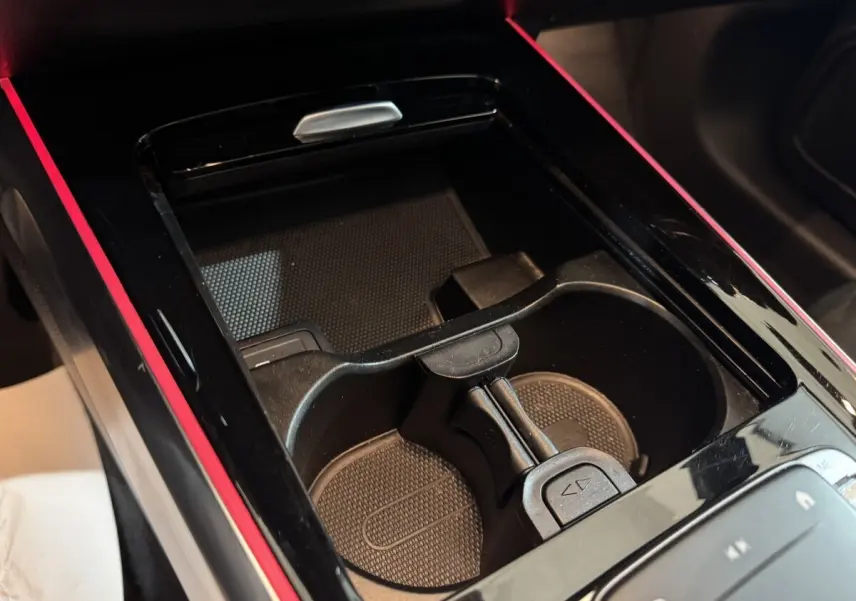 Gros plan sur la console centrale noire avec porte-gobelets et bande lumineuse rouge d’un Mercedes GLB 200 d AMG Line.