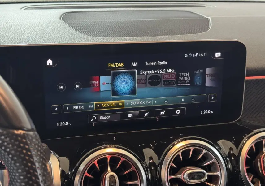 Vue rapprochée de l’écran tactile central et des aérateurs ronds chromés du tableau de bord noir du Mercedes GLB 200 d AMG Line.