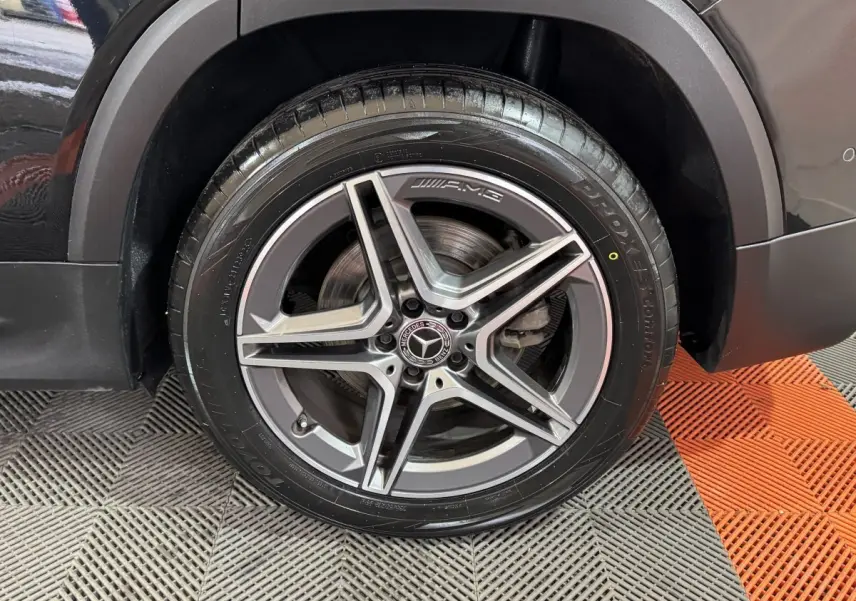 Gros plan sur la roue avant droite du Mercedes GLB 200 d AMG Line noir, mettant en valeur la jante AMG à cinq branches.