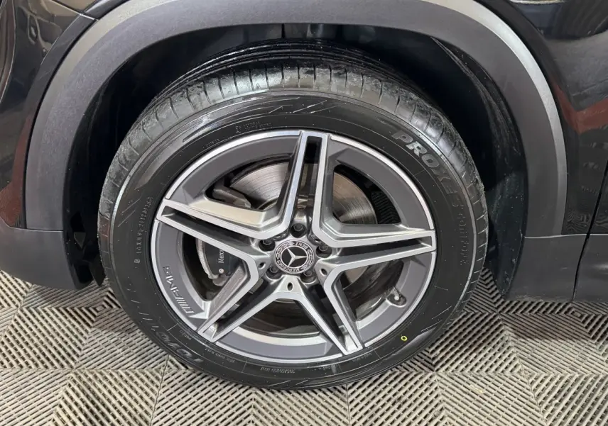 Gros plan sur la roue avant droite noire du Mercedes GLB 200 d AMG Line avec jante AMG cinq branches.