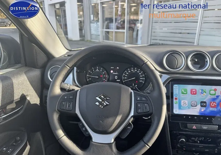 Vue intérieure centrée sur le volant cuir multifonction noir du Suzuki Vitara avec tableau de bord et écran tactile.