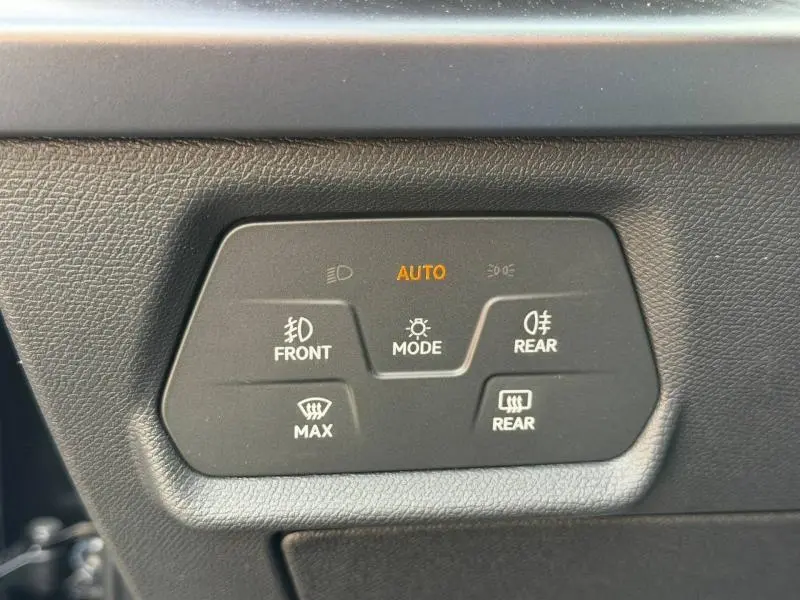 Gros plan sur les commandes d’éclairage et de désembuage du tableau de bord noir du CUPRA Formentor bleu.