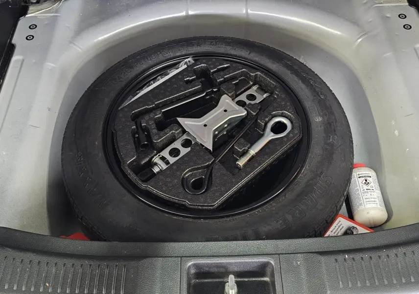 Gros plan sur la roue de secours et les outils de bord dans le coffre d'un Suzuki SX4 S-Cross gris 2020.