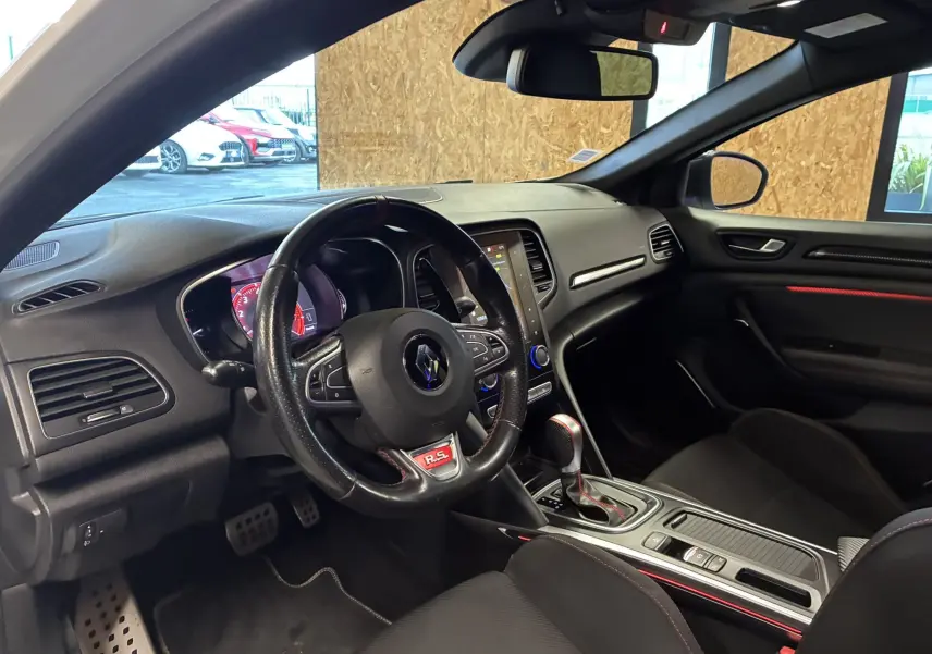 Gros plan sur la roue arrière droite noire à jante spécifique RS d’une Renault Mégane IV RS 280 blanche avec logo Renault Sport.