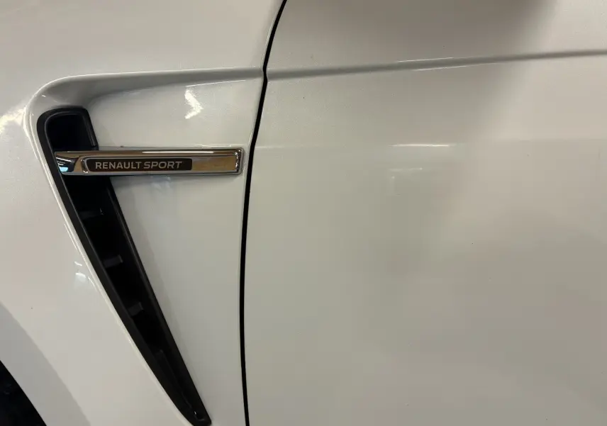 Gros plan sur la prise d'air latérale gauche blanche de la Renault Mégane IV RS 280 EDC6 avec logo Renault Sport chromé.