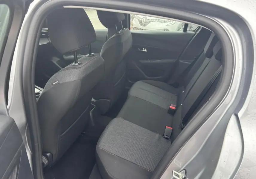 Vue intérieure côté arrière droit du Peugeot 208 gris 2025, montrant les sièges arrière en tissu bicolore.