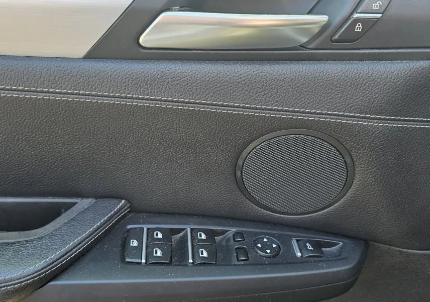 Détail de la porte côté conducteur du BMW X4 xDrive20dA 2015 noir, avec commandes de vitres et haut-parleur intégré.