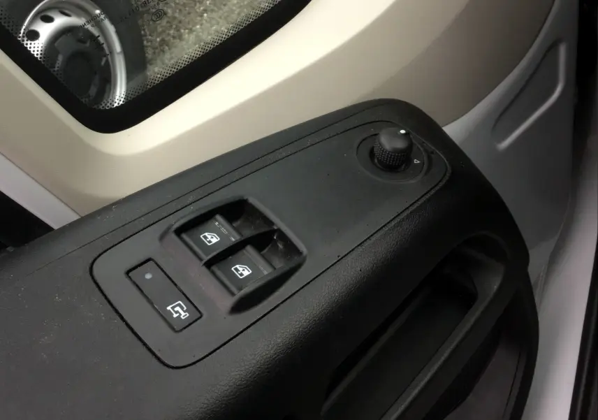 Gros plan sur les commandes de lève-vitres et réglage des rétroviseurs côté conducteur du Fiat Ducato blanc 2024.