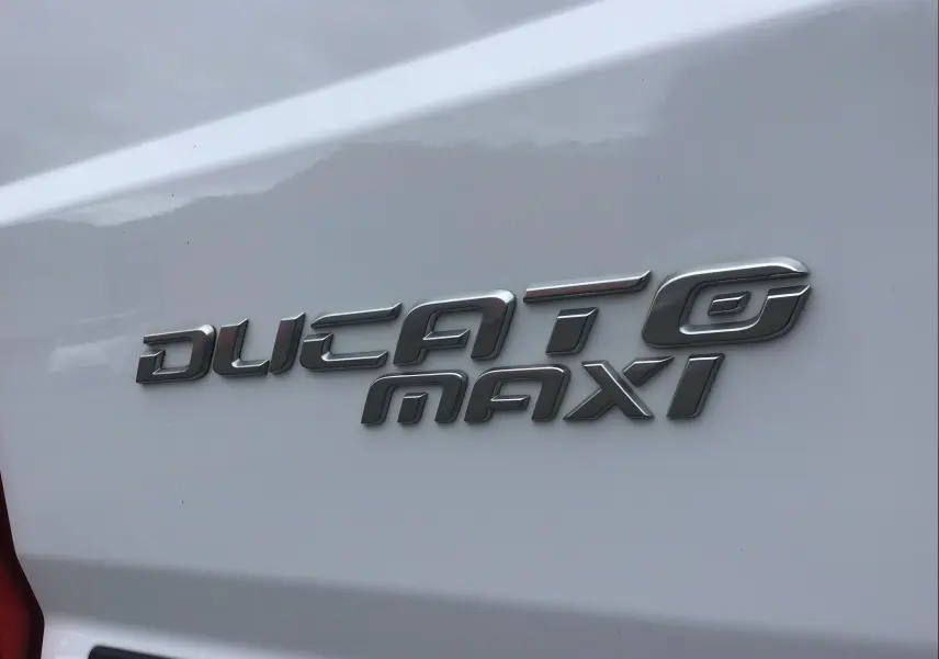 Gros plan sur l’inscription argentée "Ducato Maxi" sur la carrosserie blanche arrière du FIAT Ducato Fourgon.