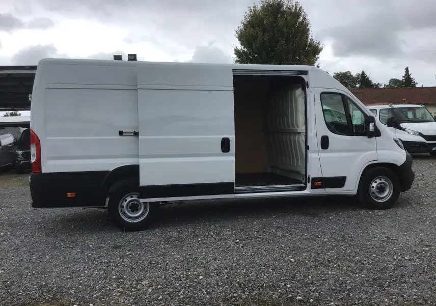 Fourgon FIAT Ducato blanc vu de profil côté gauche, porte latérale coulissante ouverte montrant l'intérieur vide.