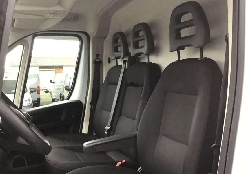 Vue intérieure côté conducteur du Fiat Ducato Fourgon blanc 2024, montrant les trois sièges noirs avec appuie-têtes.