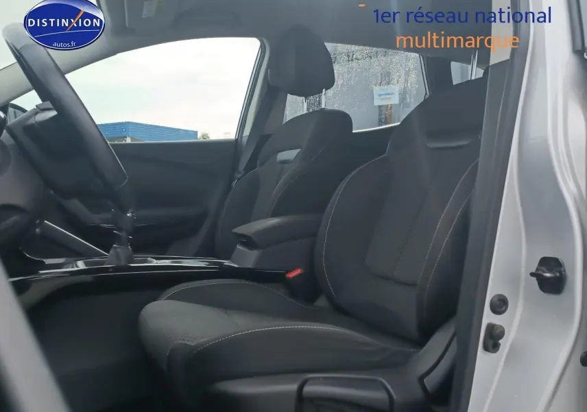 Intérieur vue côté gauche montrant les sièges avant noirs et l'accoudoir central du Renault Kadjar gris 2017.