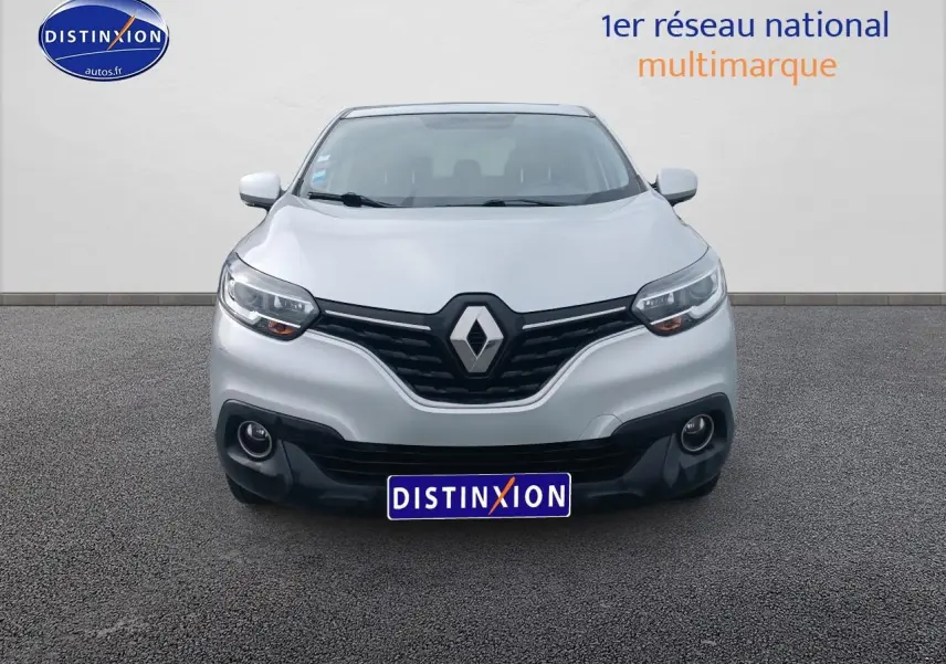 Vue frontale d'un Renault Kadjar gris avec calandre noire et phares allumés sur fond neutre.