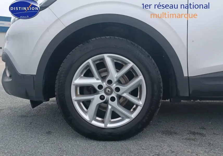 Gros plan sur la roue avant gauche en jante alu du Renault Kadjar gris, avec partie basse de la carrosserie visible.