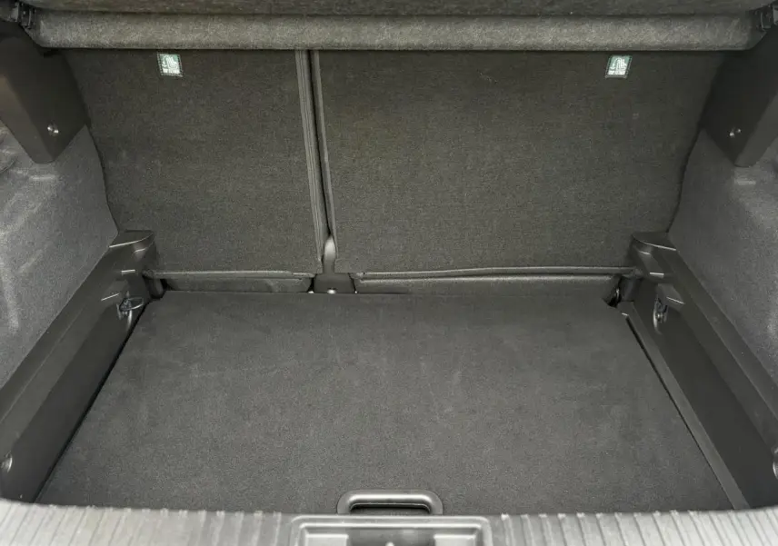 Coffre spacieux du Renault Captur 2025 vu de face, revêtement noir avec plancher plat et fixations ISOFIX visibles.