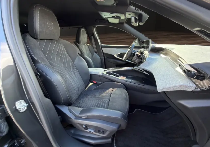 Vue intérieure côté conducteur du Peugeot 5008 2025, sièges Alcantara gris foncé avec logo Peugeot brodé.