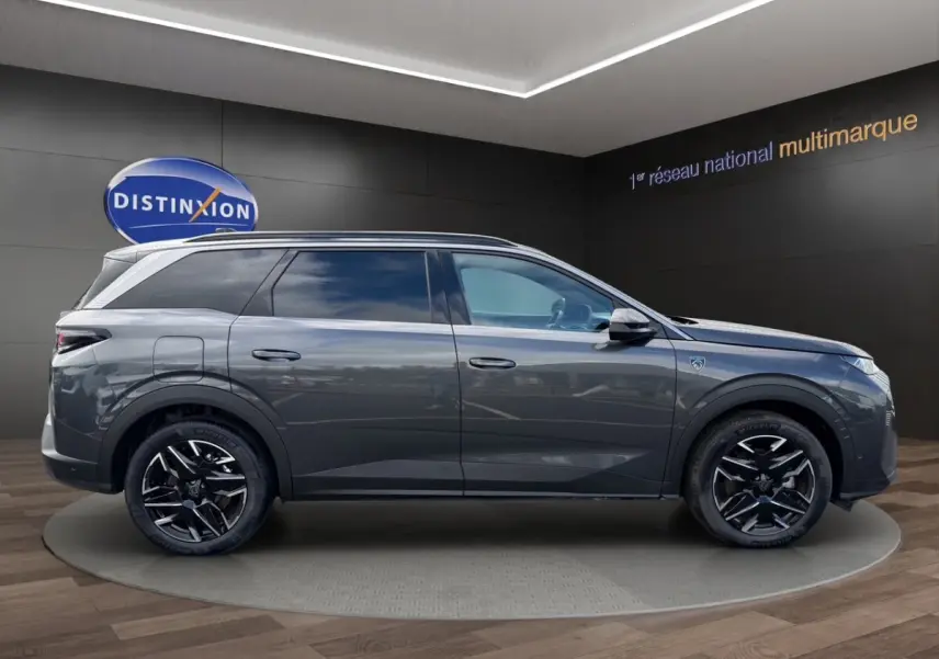 Vue latérale droite du Peugeot 5008 gris foncé avec jantes noires et toit équipé de rails assortis.